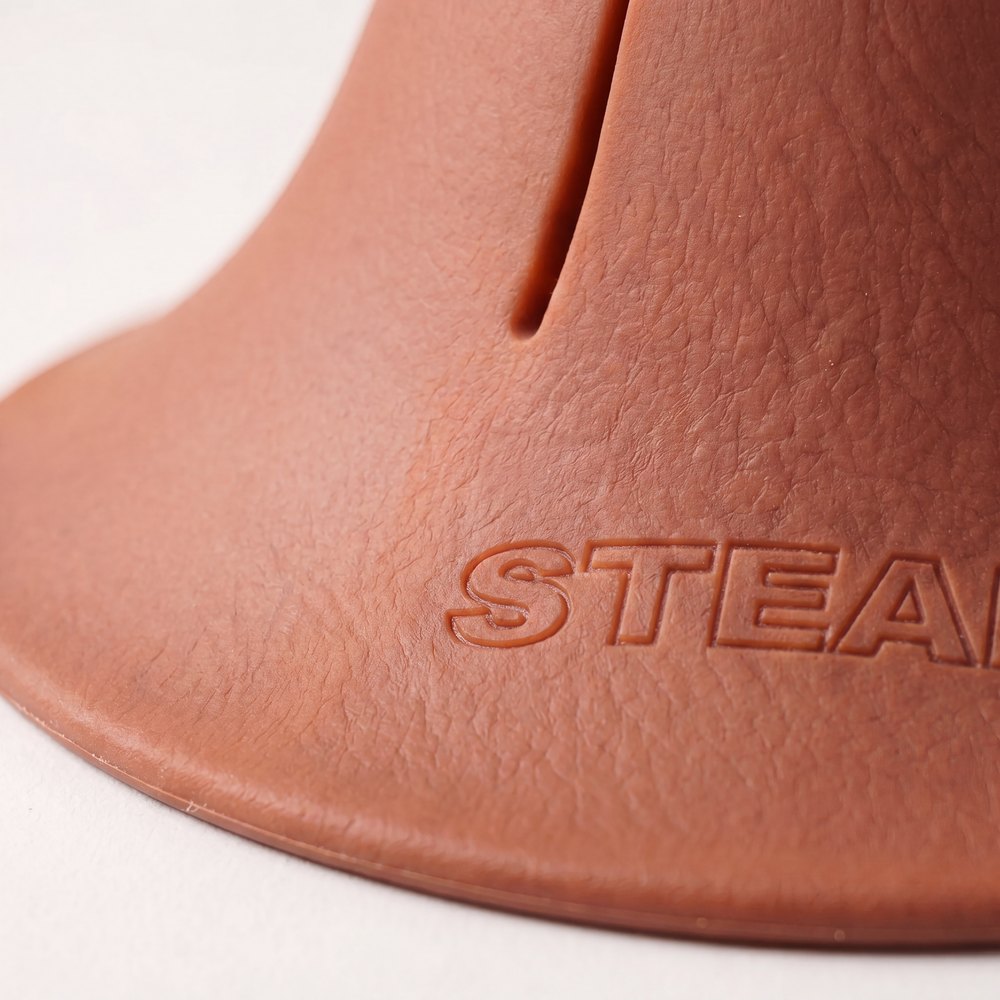 Macro photograph of the flared foot of a copper Steadi, showing the moulded STEADI mark and the texture of the TPU.